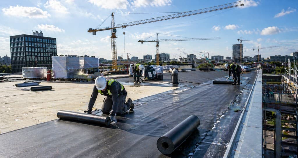Dakdekkers die dakbedekking aanbrengen op een groot bedrijfspand